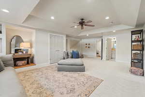 Living area featuring carpet floors, recessed lighting, a raised ceiling, and a ceiling fan