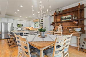 Dining room featuring ornamental molding, light wood-type flooring, recessed lighting, and a chandelier