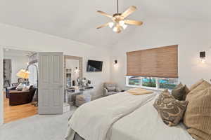 Carpeted bedroom with a ceiling fan and high vaulted ceiling