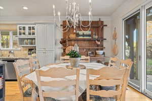 Dining area featuring light wood-type flooring, ornamental molding, and a chandelier