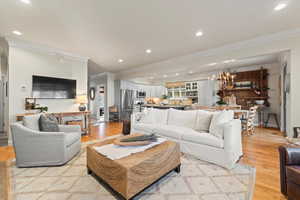 Living area with crown molding, light wood finished floors, recessed lighting, and a chandelier