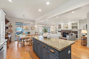 Kitchen with crown molding, a fireplace, light stone counters, hanging light fixtures, and recessed lighting