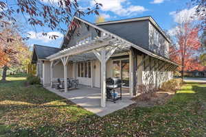 Back of house with a pergola, a lawn, a patio, and stucco siding