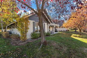 View of property exterior featuring a lawn, a patio area, and stucco siding