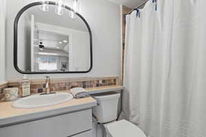 Full bathroom featuring vanity, a shower with shower curtain, a ceiling fan, and backsplash