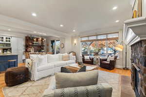 Living room featuring a fireplace, ornamental molding, light wood-type flooring, recessed lighting, and a chandelier