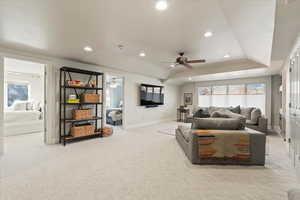 Living room featuring a raised ceiling, light carpet, recessed lighting, and ceiling fan