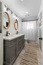 Bathroom with double vanity and shower / bath combo with shower curtain