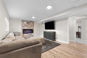 Living room featuring a fireplace, wood finished floors, wood walls, and an accent wall