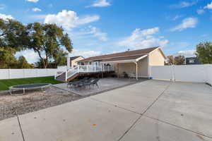 Back of house with a trampoline, a patio area, a deck, a gate, and a fenced backyard