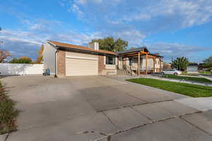 Ranch-style home featuring brick siding, concrete driveway, an attached garage, and a chimney