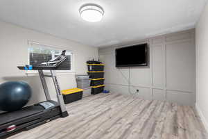 Exercise room with light wood-type flooring and a decorative wall