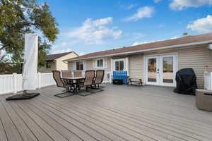 Wooden deck with outdoor dining area, grilling area, and french doors