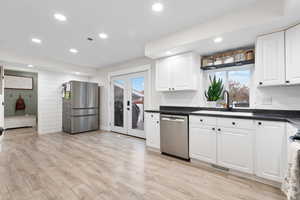 Kitchen featuring white cabinets, stainless steel appliances, recessed lighting, french doors, and light wood-style floors