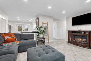 Living area with recessed lighting, light wood finished floors, a glass covered fireplace, french doors, and a wainscoted wall