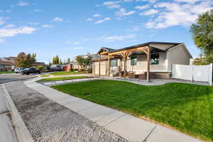 View of front facade with a front lawn, an attached garage, driveway, and a porch