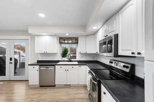 Kitchen featuring appliances with stainless steel finishes, recessed lighting, white cabinets, french doors, and light wood-style floors