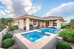 Rear view of property featuring an outdoor hangout area, stucco siding, a patio area, and a pool with connected hot tub