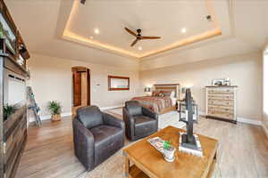 Primary Bedroom with a raised ceiling, arched walkways, light wood-style floors, a ceiling fan, and recessed lighting