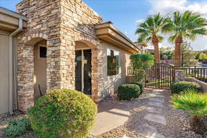 Private entrance to property with stucco siding, stone siding, and a gate