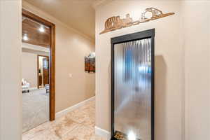 Foyer featuring crown molding, light tile patterned floors, and light colored carpet
