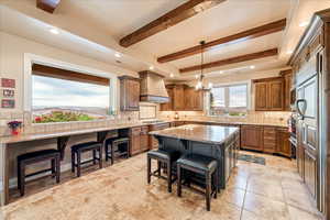 Kitchen featuring a kitchen bar, light stone counters, a center island, tasteful backsplash, and brown cabinetry
