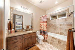 Guest Bathroom featuring vanity, tiled shower / bath combo, light tile patterned flooring, and ceiling fan