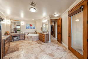 Primary bathroom featuring two vanities, a bath, crown molding, and light tile patterned floors