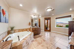 Primary Bathroom with vanity, crown molding, a tub with jets, light tile patterned floors, and a mountain view
