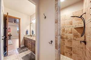 Guest Suite Full bathroom with walk in shower, vanity, light tile patterned floors, and ceiling fan