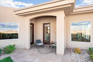 View of private exterior entry featuring stucco siding and a patio area