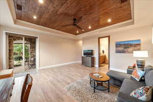 Living room featuring wood ceiling, a raised ceiling, recessed lighting, light wood-type flooring, and crown molding