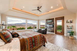 Primary Bedroom featuring access to exterior, a raised ceiling, light wood-style floors, a ceiling fan, and crown molding