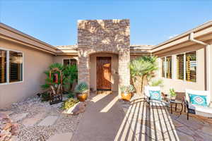 Doorway to property featuring stucco siding and stone siding