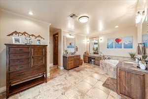 Primary Bathroom featuring ornamental molding, a bath, two vanities, light tile patterned floors, and recessed lighting