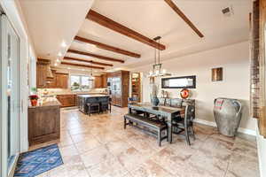 Dining area with beam ceiling, a chandelier, and light tile patterned flooring