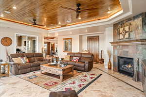 Living room with wooden ceiling, a fireplace, recessed lighting, a tray ceiling, and crown molding