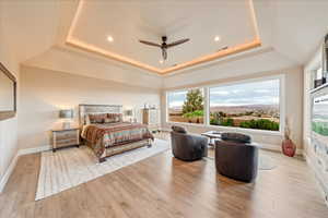 Primary Bedroom with a tray ceiling, light wood finished floors, a ceiling fan, recessed lighting, and crown molding