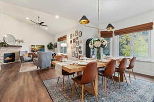 Dining space featuring dark wood finished floors, high vaulted ceiling, a fireplace, a ceiling fan, and recessed lighting