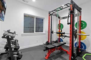 Exercise room featuring dark rubber floors and baseboards