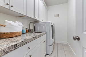 Laundry area featuring cabinet space, light tile patterned floors, and washer and clothes dryer