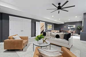 Living room with carpet flooring, recessed lighting, a ceiling fan, and stairs