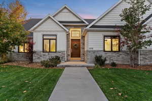 Exterior entry at dusk featuring board and batten siding, stone siding, and a yard
