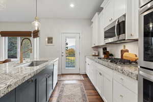 Kitchen with white cabinets, pendant lighting, appliances with stainless steel finishes, and recessed lighting