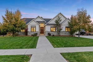 View of front of property featuring stone siding, a yard, and board and batten siding