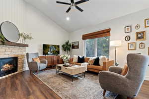 Living area featuring wood finished floors, a fireplace, high vaulted ceiling, recessed lighting, and a ceiling fan
