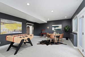 Recreation room with light carpet and recessed lighting