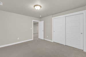 Unfurnished bedroom featuring carpet, a textured ceiling, and a closet