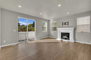 Unfurnished living room featuring recessed lighting, a glass covered fireplace, plenty of natural light, and light wood-style flooring