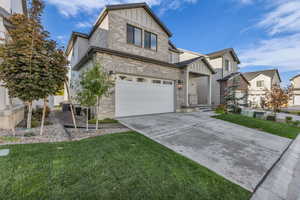 View of front of home with brick siding, concrete driveway, a front lawn, and board and batten siding